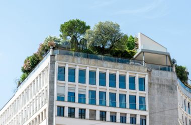 A modern building featuring lush rooftop gardens under a clear blue sky.
